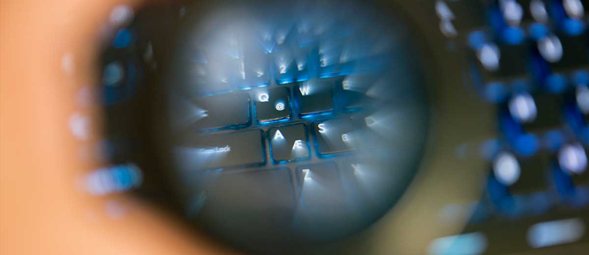 Image of a magnifying glass looking at a computer keyboard.