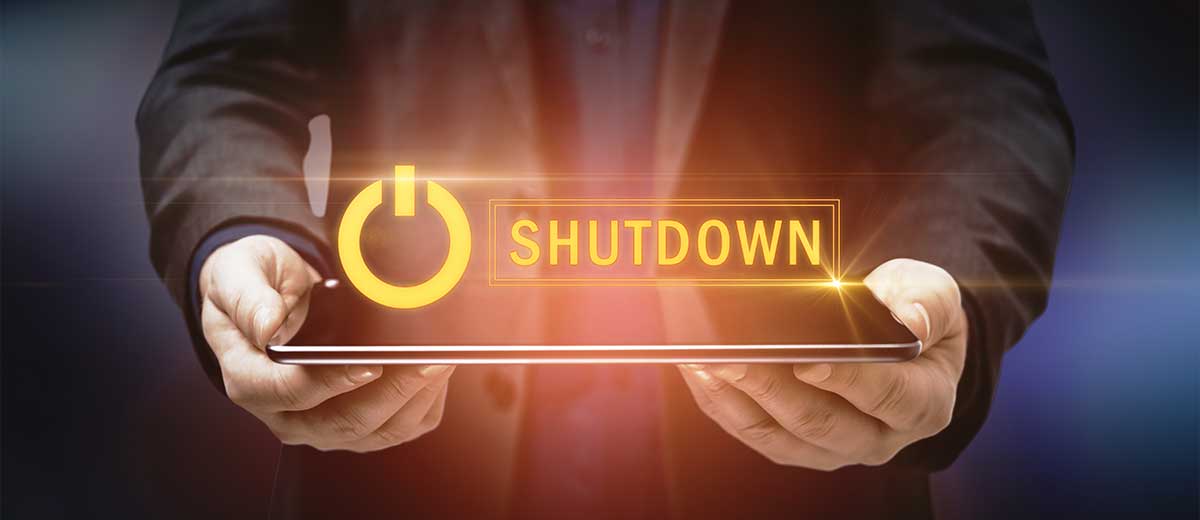 Image of a person holding a closed laptop with the words "Shut Down" hovering over the laptop.